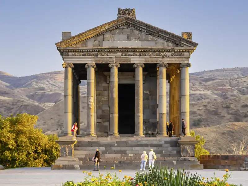 Der römisch-hellenistische Tempel von Garni, eine Sehenswürdigkeit, die auf unserer Armenienreise besichtigt wird, steht vor einer hügeligen Landschaft.