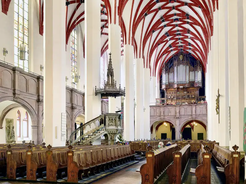 Auf unserer Gruppenreise mit Studiosus bewundern wir die Innenansicht der Thomaskirche in Leipzig, mit Blick auf die Kirchenbänke, die Kanzel und die Orgel. Ein kulturelles Highlight unserer Städtereise nach Leipzig.