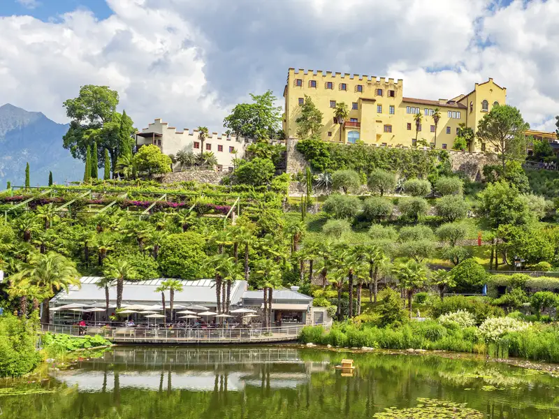 Die Gärten von Schloss Trauttmannsdorff bei Meran in Südtirol mit mediterraner Vegetation, See und dem historischen Schloss, ein Highlight unserer Gruppenreise mit Studiosus nach Südtirol.