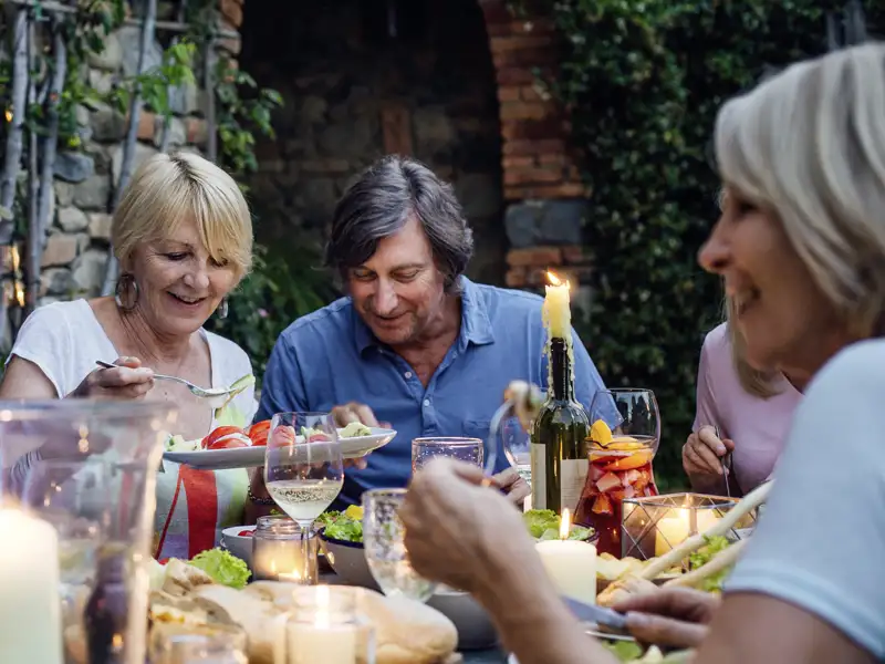 Eine Gruppe von Reisenden genießt ein gemeinsames Abendessen bei Kerzenschein, eineauf unserer Gruppenreise mit Studiosus inkludierte Leistung, bei der lokale Spezialitäten serviert werden.