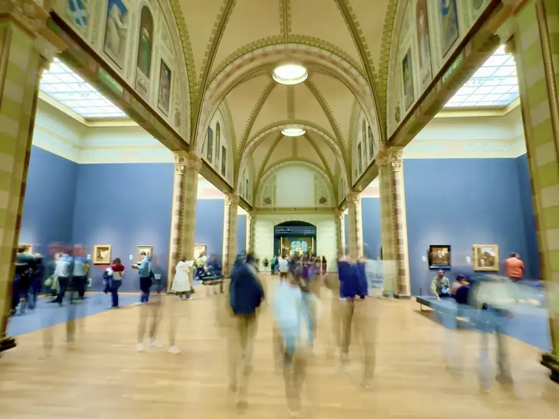 Prunkvolle Ehrengalerie im Rijksmuseum Amsterdam mit Gewölbedecke, Kunstwerken an den Wänden und bewegungsunscharfen Besuchern, ein Highlight auf unserer Gruppenreise mit Studiosus.