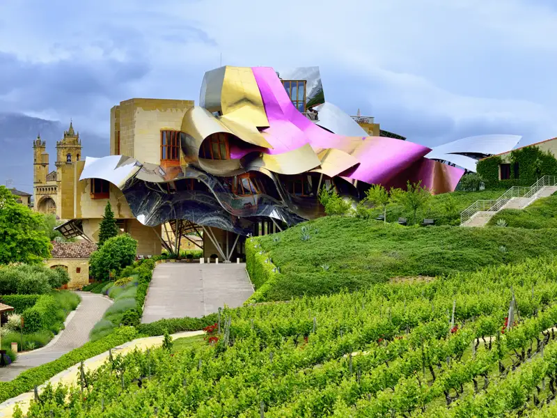 Das Hotel der Bodega Marqués de Riscal in der Rioja mit seinen geschwungenen Dächern aus Titan inmitten grüner Weinreben, ein Hingucker, der uns auf unserer Studiosus Kulturreise nach Spanien begegnet