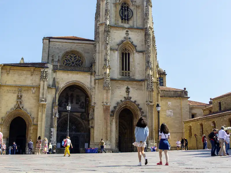 Teilnehmer einer Studienreise besichtigen die imposante gotische Kathedrale von Oviedo in Asturien bei Sonnenschein.