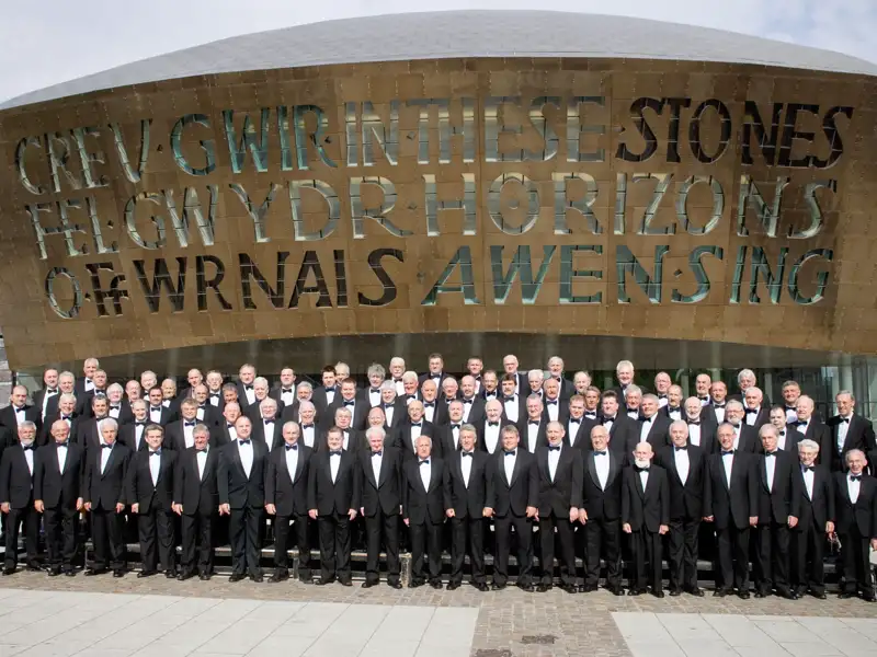 Der Treorchy Male Voice Choir posiert für ein Gruppenfoto vor dem modernen Wales Millennium Centre in Cardiff, ein Stopp auf unserer Eventreise mit Studiosus.