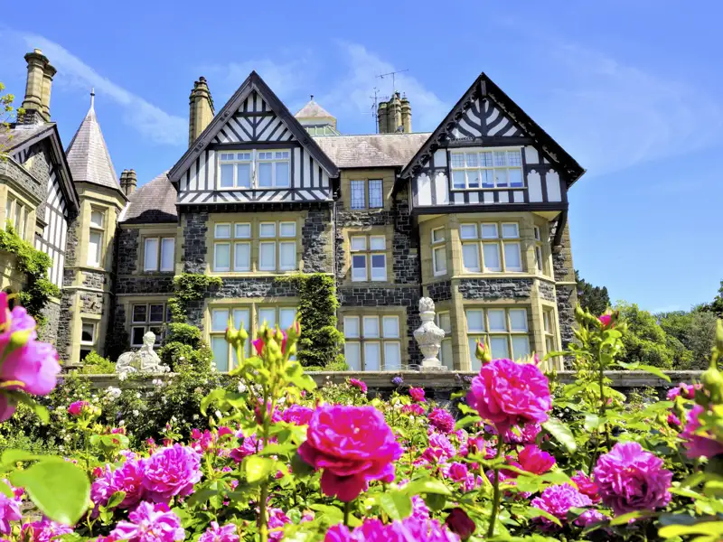 Blühender Rosengarten vor dem historischen Herrenhaus Bodnant House im Tudor-Stil im Bodnant Garden in Nordwales, ein Highlight jeder Gruppenreise mit Studiosus.