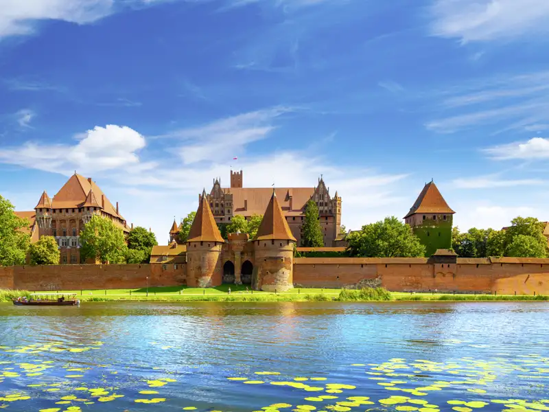 Die imposante Backsteingotik der Marienburg in Malbork, UNESCO-Welterbe, am Ufer des Flusses Nogat in Polen, ein Highlight unserer Gruppenreise mit Studiosus.