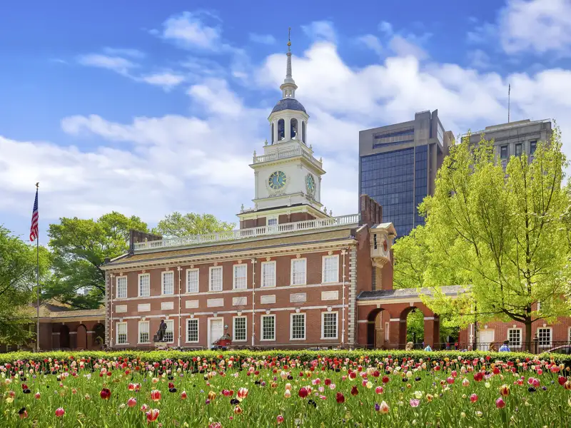 Die historische Independence Hall in Philadelphia, UNESCO-Welterbe, an einem sonnigen Tag hinter einem farbenfrohen Tulpenbeet, ein toller Stopp auf unserer Gruppenreise in die USA mit Studiosus.