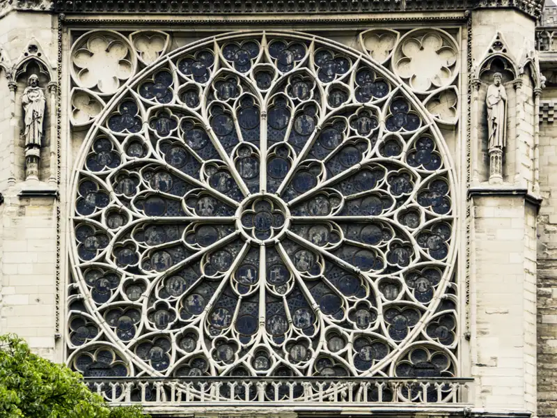 Detailansicht des gotischen Rosettenfensters mit filigranem Maßwerk an der Steinfassade der Kathedrale Notre-Dame in Paris, welches wir auf unserer Rundreise nach Paris entdecken