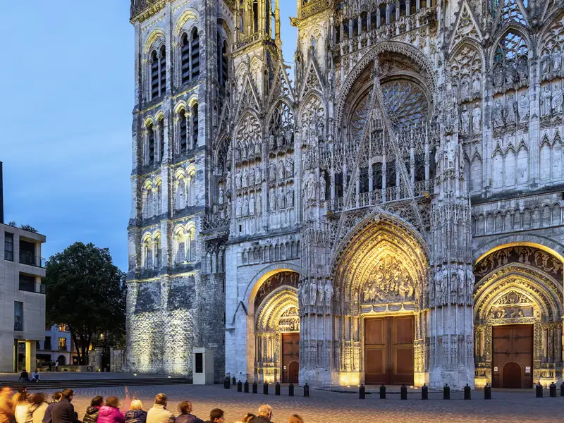 Auf unserer Rundreise mit Studiosus in die Normandie betrachten wir bei Dämmerung die kunstvoll beleuchtete Westfassade der Kathedrale von Rouen.