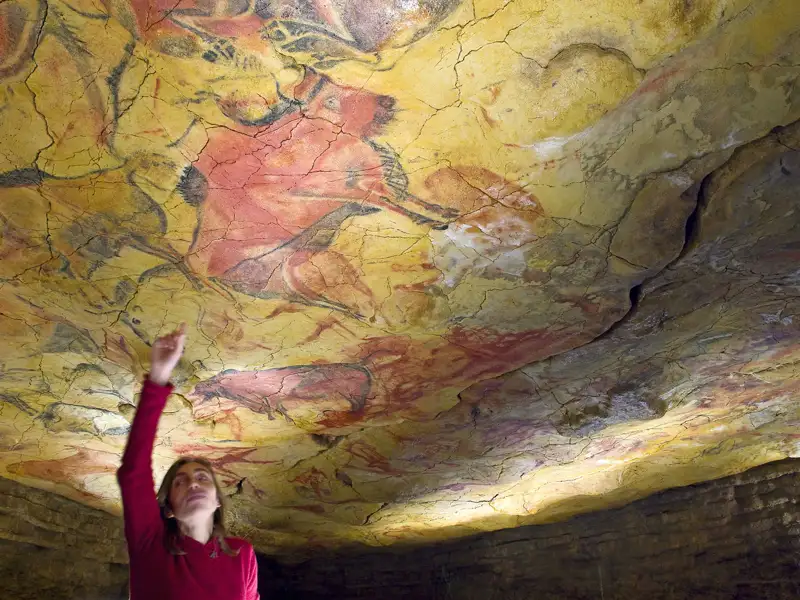 Eine Reiseleiterin zeigt auf die farbenprächtigen, prähistorischen Tiermalereien in der Nachbildung der Höhle von Lascaux, ein weiterer Stopp auf unserer Rundreise durch Spanien mit Studiosus.