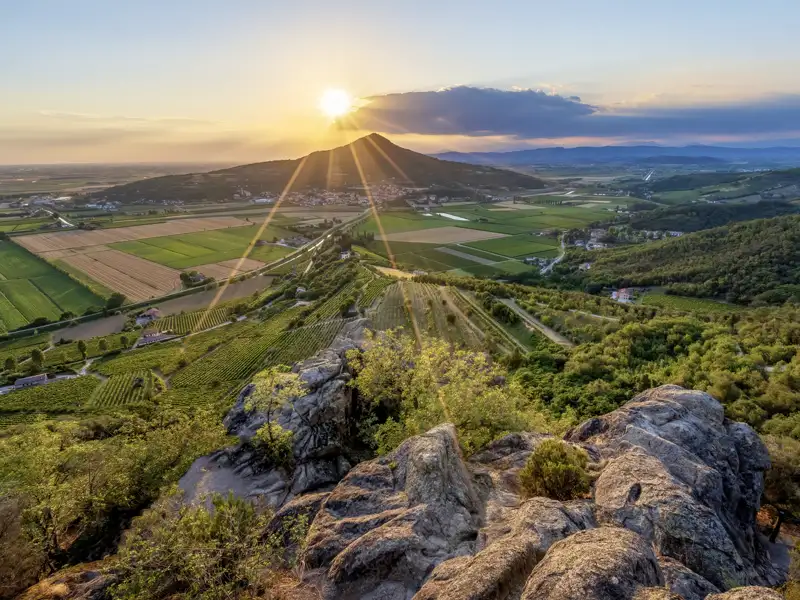 Auf unserer Rundreise nach Italien genießen wir den malerischen Sonnenuntergang über den Euganeischen Hügeln in Venetien mit dramatischen Sonnenstrahlen über Weinbergen.