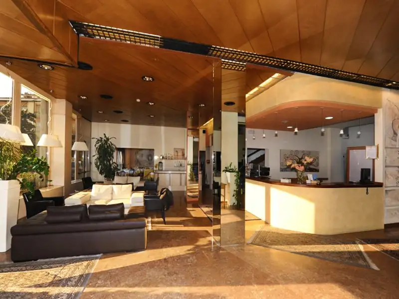 Die helle, einladende Lobby des Hotel Italia in Verona mit Rezeption, modernen Sofas und markanter Holzdecke.