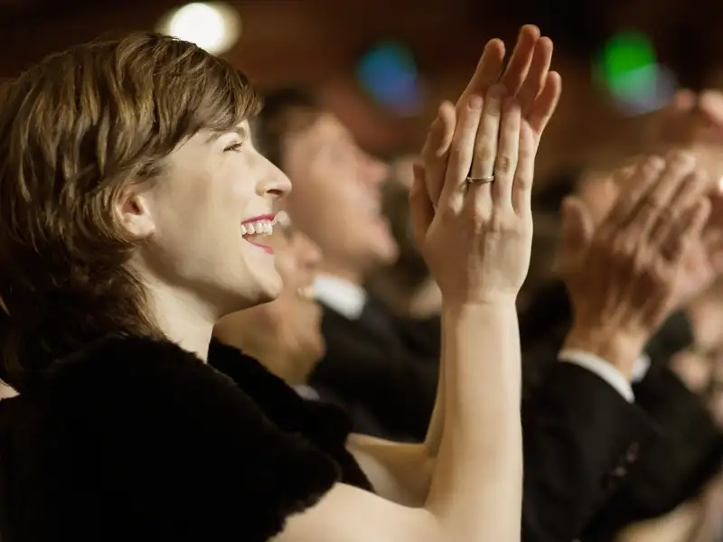 Begeisterte Frau auf einer Eventreise applaudiert im Publikum der Opernfestspiele in Verona.