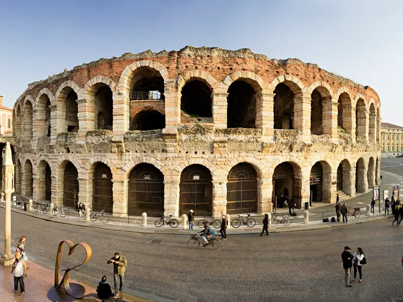 Die imposante, sonnenbeschienene Arena di Verona auf der Piazza Bra, umgeben von Menschen auf einer unvergesslichen Eventreise.