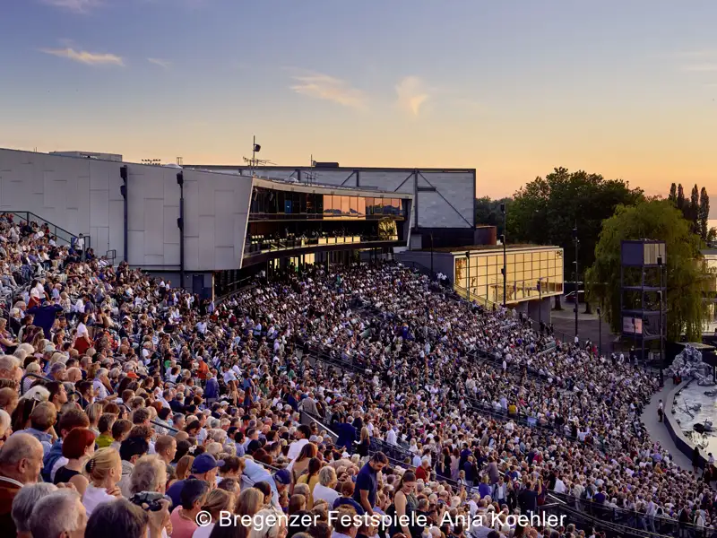 Die vollbesetzte Tribüne der Seebühne der Bregenzer Festspiele am Bodensee während des Sonnenuntergangs vor einer Vorstellung, ein Highlight unserer Eventreise.