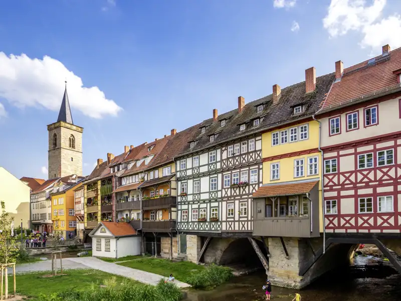 Sonnige Ansicht der bunten Fachwerkhäuser auf der historischen Krämerbrücke in Erfurt, im Hintergrund der Turm der Ägidienkirche, ein Highlight jeder Studiosus Gruppenreise.