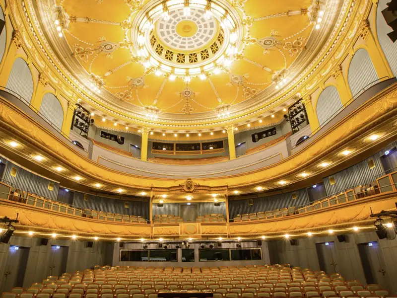 Der leere Zuschauerraum des Meininger Staatstheaters mit prunkvollen goldenen Logen und einer verzierten Deckenkuppel, ein Highlight unserer Eventreise mit Studiosus.