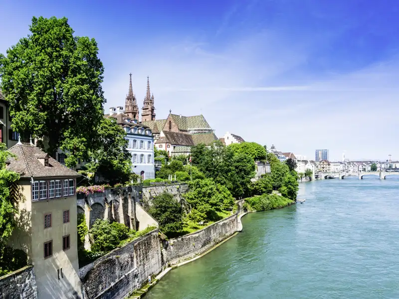 Historische Altstadt von Basel am Rheinufer mit dem markanten Basler Münster unter strahlend blauem Himmel, ein schöner Ausblick während unserer Studiosus Gruppenreise nach Basel.