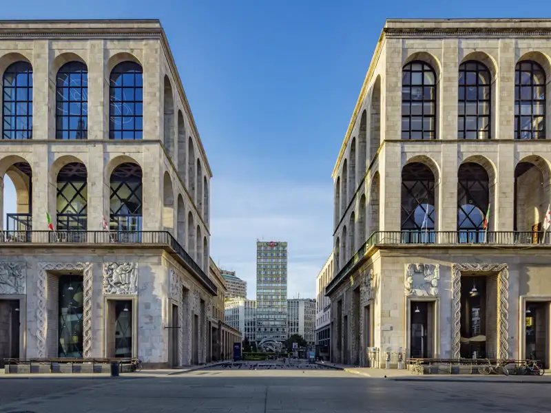 Auf unserer Eventreise mit Studiosus nach Italien bewundern wir symmetrische Fassaden des Palazzo dell’Arengario in Mailand mit großen Rundbogenfenstern und Blick auf die Torre Velasca.
