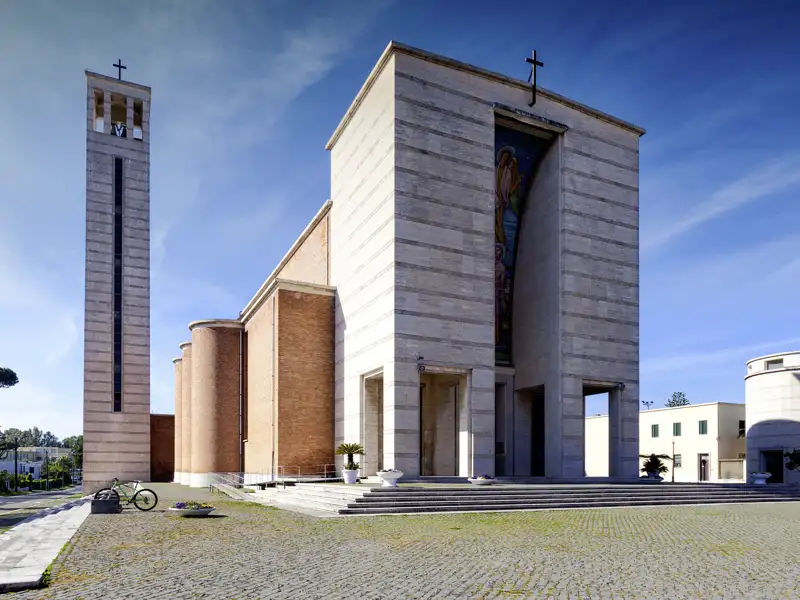 Auf unserer Rundreise mit Studiosus durch Italien sehen wir die rationalistische Kirche Santissima Annunziata in der Planstadt Sabaudia mit separatem Glockenturm und Mosaikfassade.