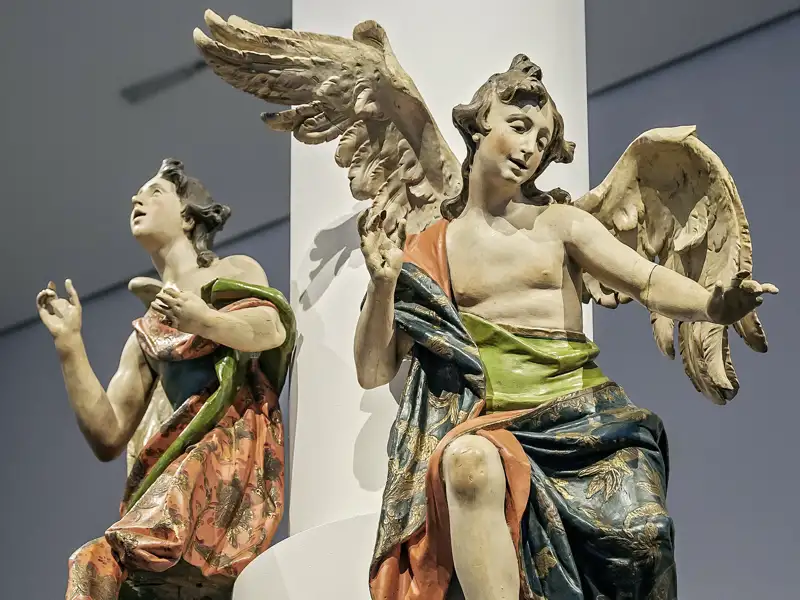 Zwei detailreiche barocke Engelsfiguren mit ausdrucksstarker Gestik in der Ausstellung des Bayerischen Nationalmuseums München, ein Highlight der Gruppenreise mit Studiosus.
