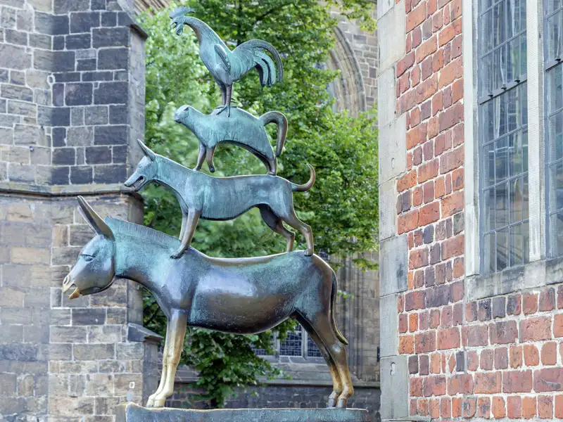 Die Bronzestatue der Bremer Stadtmusikanten, ein Wahrzeichen Bremens, steht vor der historischen Backsteinfassade des Rathauses, ein Highlight auf jeder Studiosus Gruppenreise.