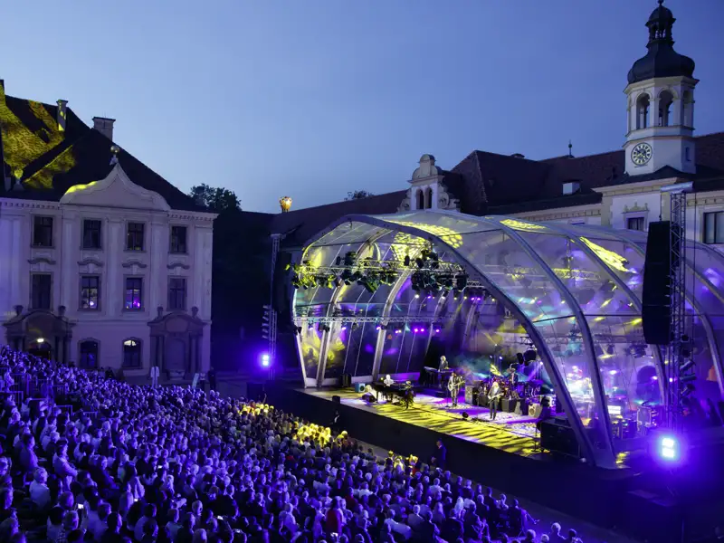 Publikum bei einer Operngala der Schlossfestspiele Regensburg im festlich beleuchteten Innenhof von Schloss St. Emmeram, ein Highlight unserer Eventreise mit Studiosus.