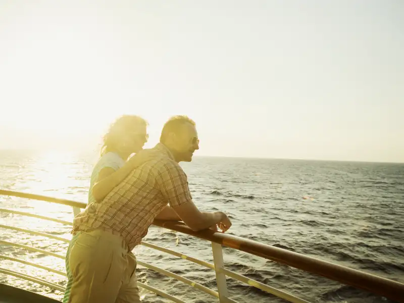 Von der Reeling des Dampfers blickt ein Paar aufs Wasser.