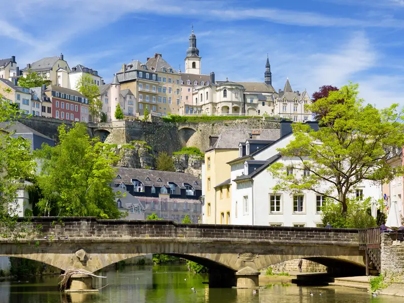 Historische Gebäude und Festungsmauern der Altstadt von Luxemburg erheben sich über dem Fluss Alzette und einer Steinbrücke, ein Highlight unserer Städtereise mit Studiosus.
