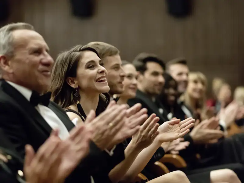 Elegant gekleidete Reisegäste klatschen als Publikum bei einer Abendvorstellung, die wir auf unserer Eventreise mit Studiosus besuchen.