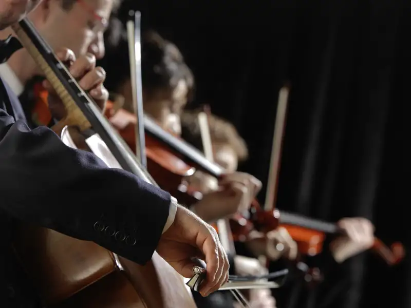 Streicher eines Orchesters spielen Cello und Geige während einer Puccini-Opernaufführung auf einer Eventreise in Italien.