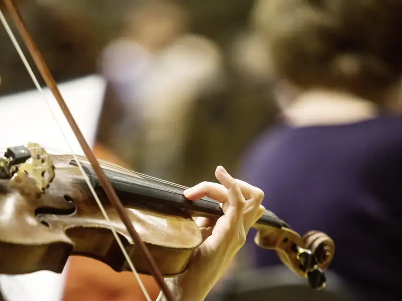 Nahaufnahme einer Musikerin, die bei einem Konzert der Slowakischen Philharmonie in der Reduta in Bratislava Violine spielt, ein musikalisches Highlight unserer Eventreise mit Studiosus.