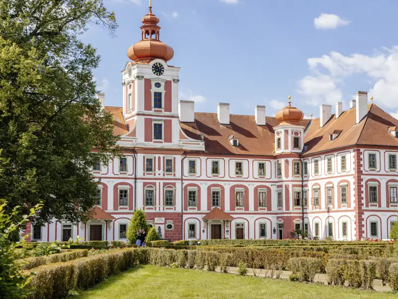 Auf unserer Gruppenreise mit Studiosus bewundern wir das Barockschloss Mnichovo Hradiste im Böhmischen Paradies mit seiner rot-weißen Fassade und gepflegtem Schlossgarten.