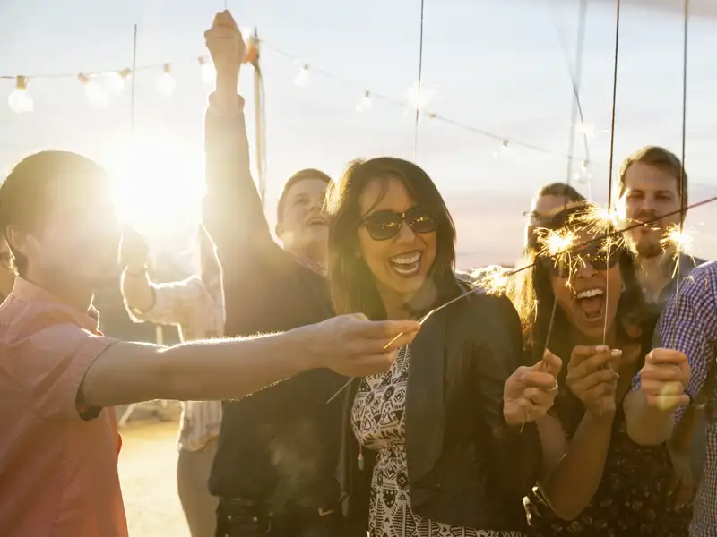 Eine fröhliche Reisegruppe feiert mit brennenden Wunderkerzen Silvester an Deck während der Kreuzfahrt zu den Kapverden.