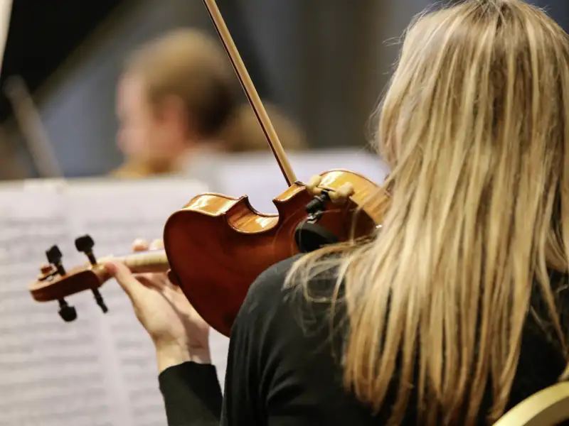 Rückansicht einer blonden Geigerin, die während eines Konzerts des Chopin-Festivals in Marienbad konzentriert Geige spielt.