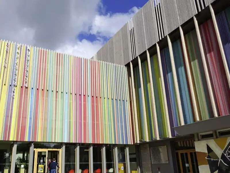Besucher betreten auf einer Studienreise die Cité de la tapisserie in Aubusson mit ihrer bunten, modernen Fassade, ein Highlight auf unserer Studienreise mit Studiosus nach Frankreich.