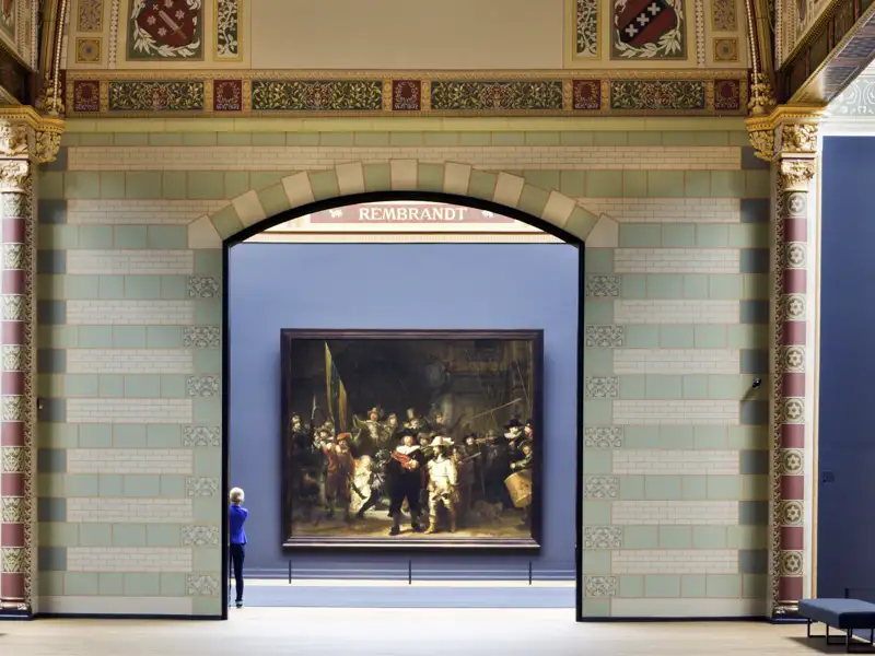 Auf einer Studienreise in Amsterdam: Blick durch einen Torbogen auf Rembrandts Gemälde 'Die Nachtwache' im Rijksmuseum.