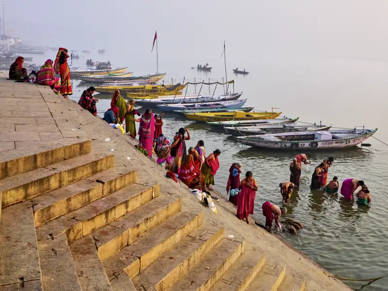 Gläubige in farbenfrohen Saris bei der morgendlichen Waschung an den steinernen Ghats des Ganges in Varanasi, ein Erlebnis auf unserer Gruppenreise mit Studiosus.