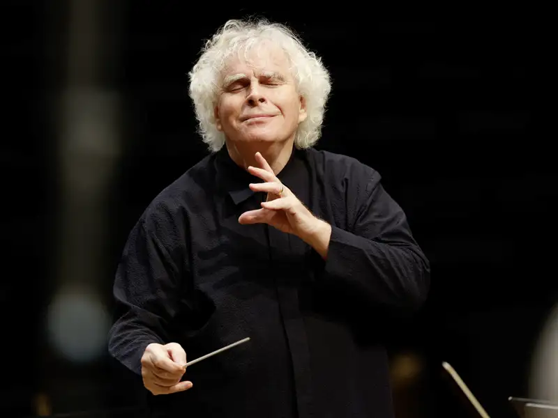 Star-Dirigent Sir Simon Rattle dirigiert beim Kissinger Sommer mit geschlossenen Augen und Taktstock ein Orchester, ein Highlight auf unserer Eventreise mit Studiosus.