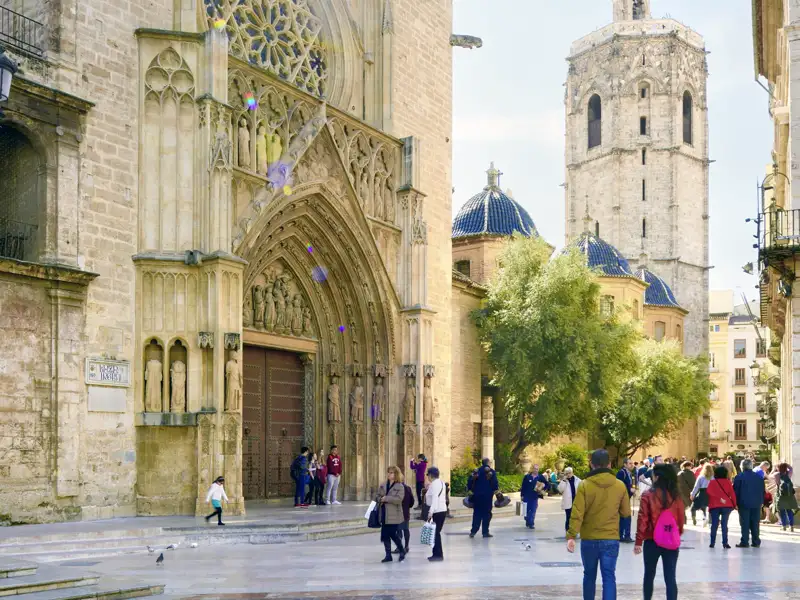 Gäste unserer Studiosus Gruppenreise nach Spanien auf der Plaza de la Virgen vor dem gotischen Apostelportal der Kathedrale von Valencia bei Sonnenschein.