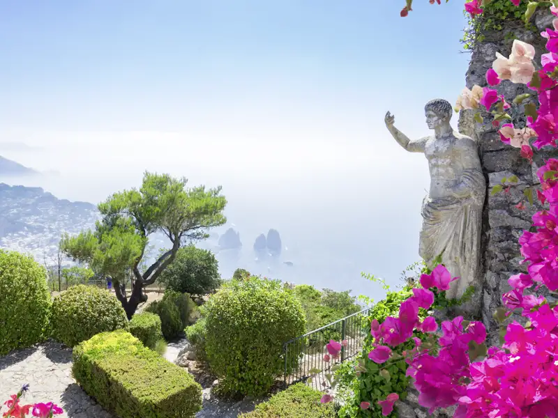 Antike Statue und pinke Bougainvillea im Garten der Villa San Michele auf Capri mit Panoramablick auf die Faraglioni-Felsen, ein Highlight unserer Gruppenreise mit Studiosus.