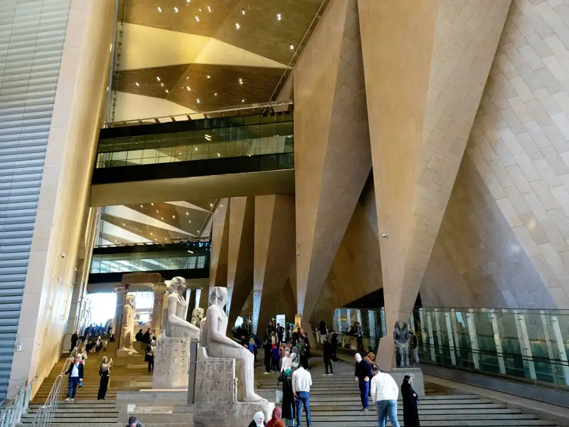 unserer Reisgruppe und andere Besucher auf der großen Treppe des Grand Egyptian Museum in Gizeh bestaunen die moderne Architektur und antike Statuen, ein Highlight unserer Eventreise nach Ägypten