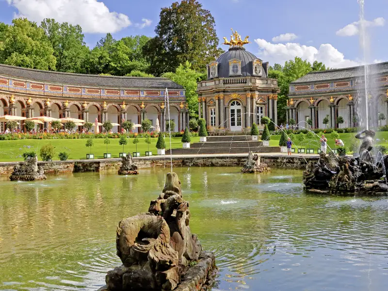 Blick über das Wasserbassin mit Fontänen auf den Sonnentempel und die Orangerie in der Parkanlage Eremitage in Bayreuth, ein Highlight unserer Gruppenreise mit Studiosus.