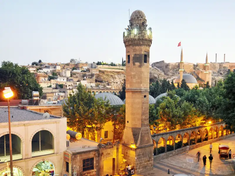 Beleuchteter Moscheenkomplex am Karpfenteich in Sanliurfa bei Dämmerung, im Hintergrund die historische Altstadt der Türkei, ein toller Anblick auf unserer Gruppenreise mit Studiosus.
