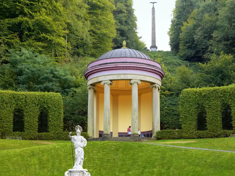 Runder Pavillon im barocken Terrassengarten von Kloster Kamp, umgeben von grünen Hecken und mit einem Obelisken im Hintergrund, ein Ausflug auf unserer Gruppenreise mit Studiosus.
