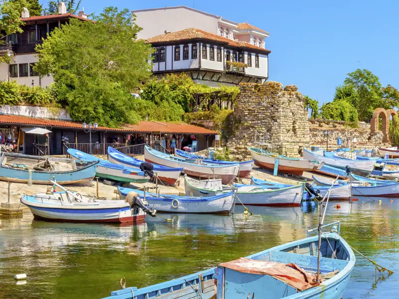 Bunte Fischerboote im Hafen der UNESCO-Stadt Nessebar vor historischen Bürgerhäusern und antiken Ruinen, ein Highlight auf unserer Gruppenreise mit Studiosus.