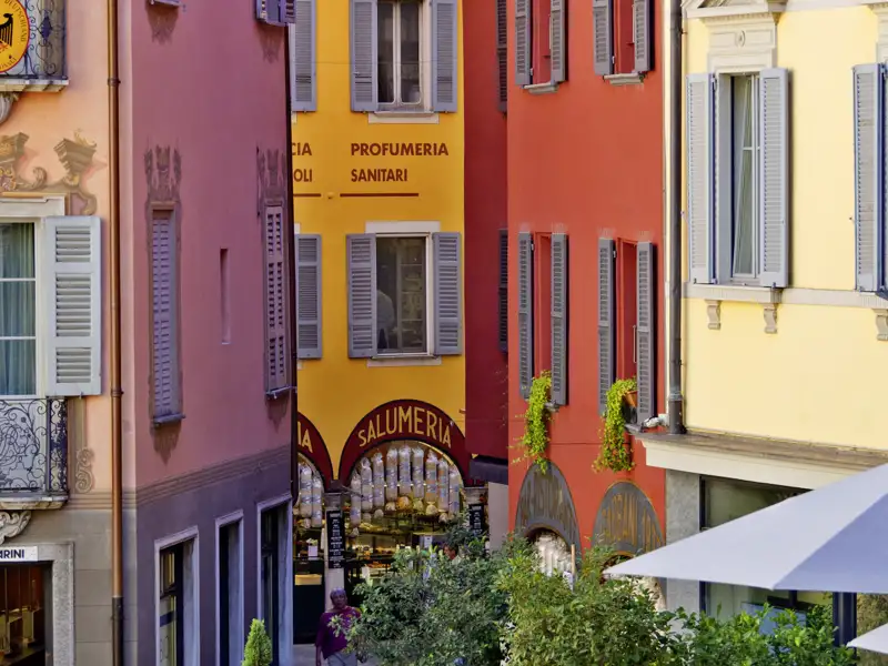 Farbenfrohe Hausfassaden mit Fensterläden in einer malerischen Gasse in Lugano, die das italienische Flair des Tessins zeigt, ein Highlight jeder Studienreise mit Studiosus.