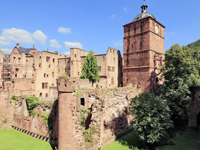 Das Heidelberger Schloss, Wahrzeichen der Romantik, mit seinen roten Sandsteinmauern und dem Torturm unter blauem Himmel, ein Highlight auf unserer Rundreise mit Studiosus.