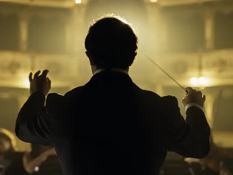 Ein Dirigent leitet von hinten gesehen mit dem Taktstock ein Orchester bei einer Aufführung in der Mailänder Scala, ein Highlight unserer Eventreise mit Studiosus.