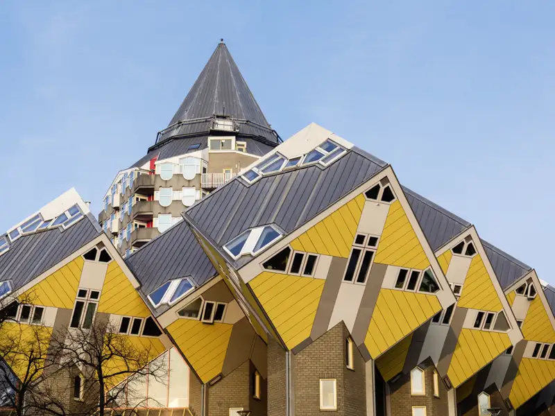 Die ikonischen, gelben Kubushäuser von Piet Blom in Rotterdam, ein Meisterwerk moderner Architektur unter blauem Himmel, ein toller Anblick auf unserer Gruppenreise in die Niedrelande.